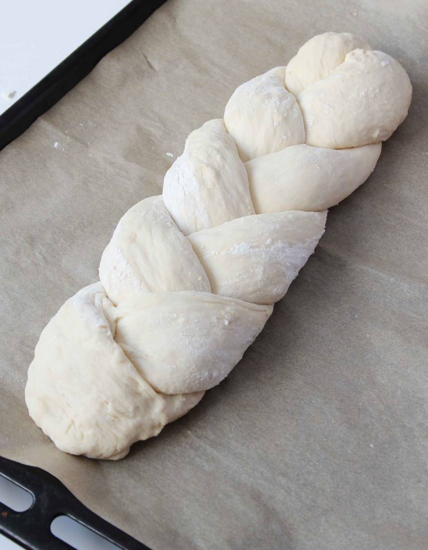 5. Fäst ihop ändarna ordentligt och lägg flätan på en plåt med bakplåtspapper. Låt den jäsa under bakduk i ca 30 min. Sätt ugnen på 200 grader.