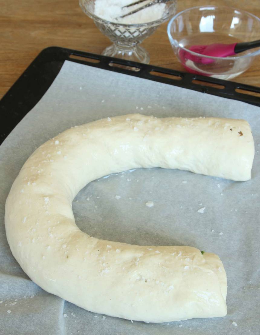 5. Lägg degrullarna lite böjda på varsin plåt med bakplåtspapper. Pensla dem med vatten och strö över flingsalt. Låt dem jäsa under bakduk i ca 30 min. Sätt ugnen på 250 grader.
