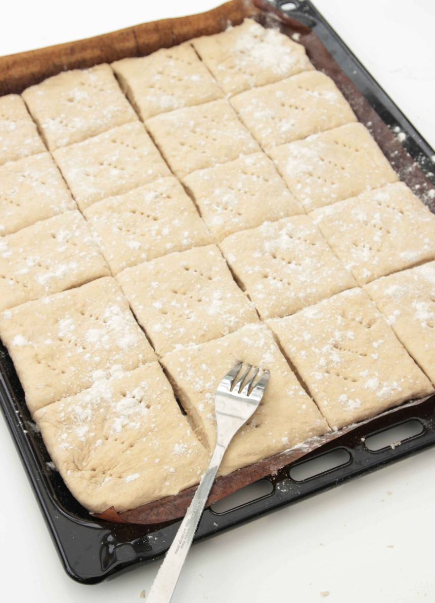 2. Tryck eller kavla ut 2/3 av degen på en ugnsplåt med bakplåtspapper. Skär degen i ett rutmönster, 5 x 4. Nagga degen med en gaffel.