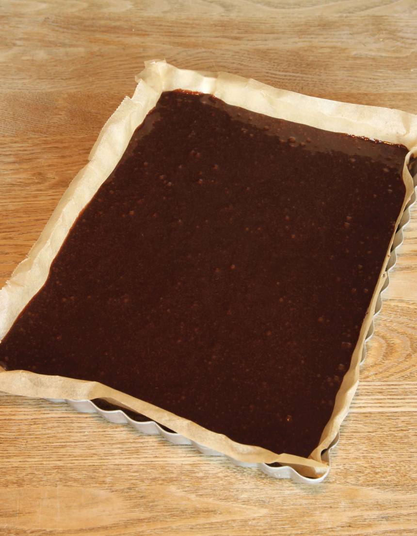 2. Lägg i ett bakplåtspapper i en form, ca 18 x 25 cm eller smörj och bröa den. Häll smeten i formen och bred ut den med en slickepott. Grädda kakan mitt i ugnen i 20–25 min. Låt den svalna i formen.
