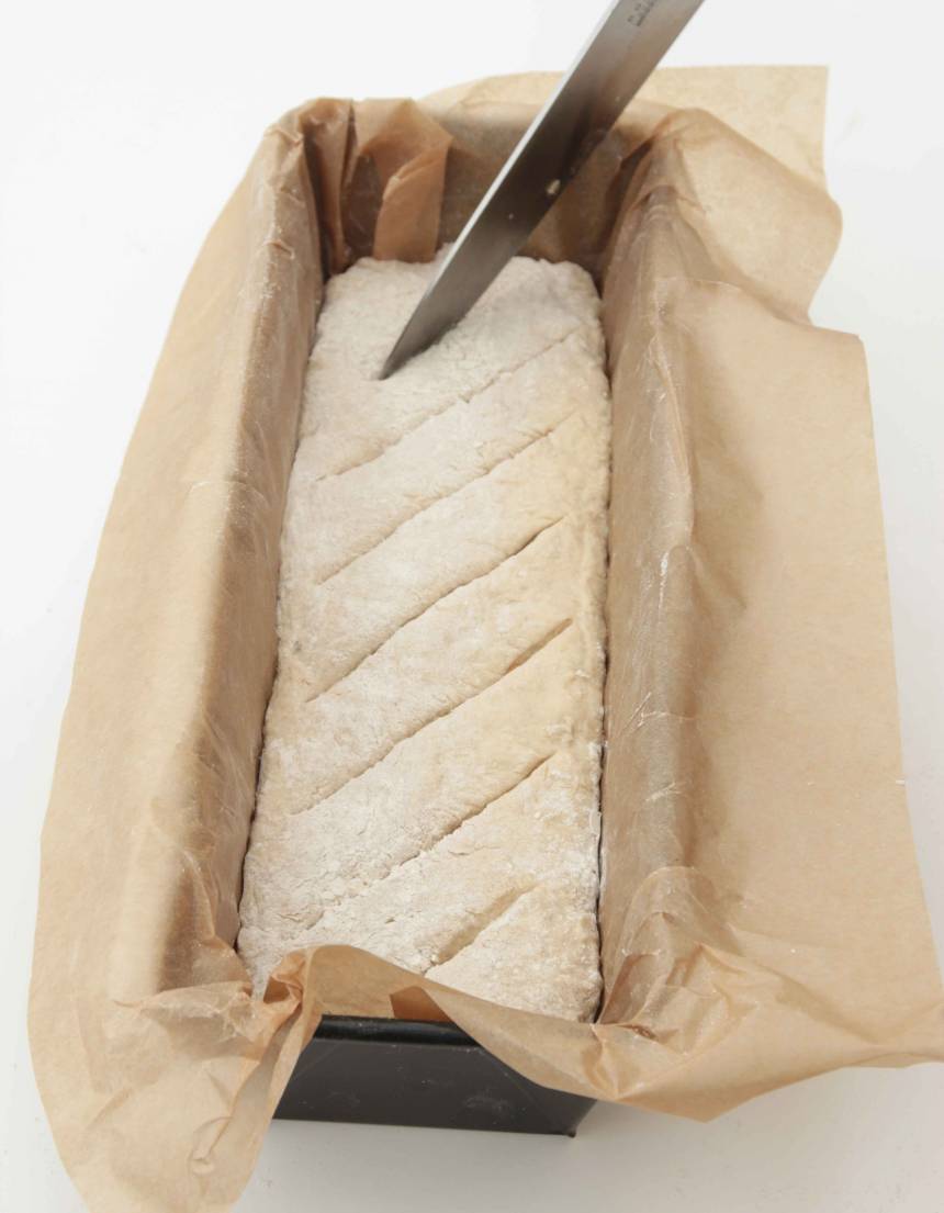 3. Forma resten av degen (1/3) till en limpa och lägg den i en limpform, ca 1 ½ liter, klädd med bakplåtspapper. Snitta ytan på limpan med en vass kniv. Låt bröden jäsa under bakduk i ca 30 min. Sätt ugnen på 230 grader.