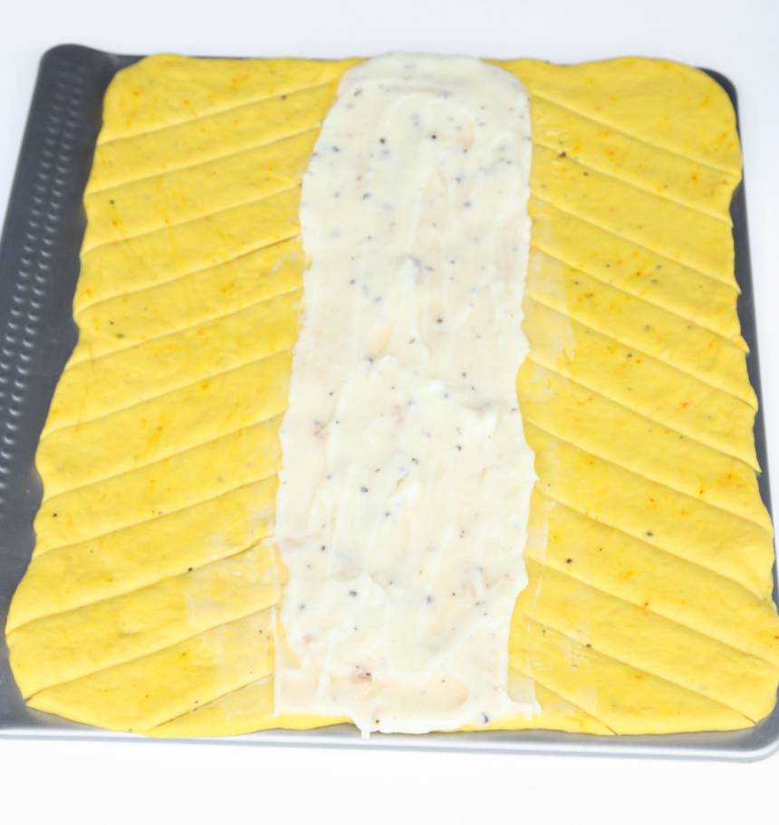 4. Bred ut vaniljkrämen i mitten av rektangeln. Skär sneda flikar i degen utifrån fyllningen, ca 2 cm breda.