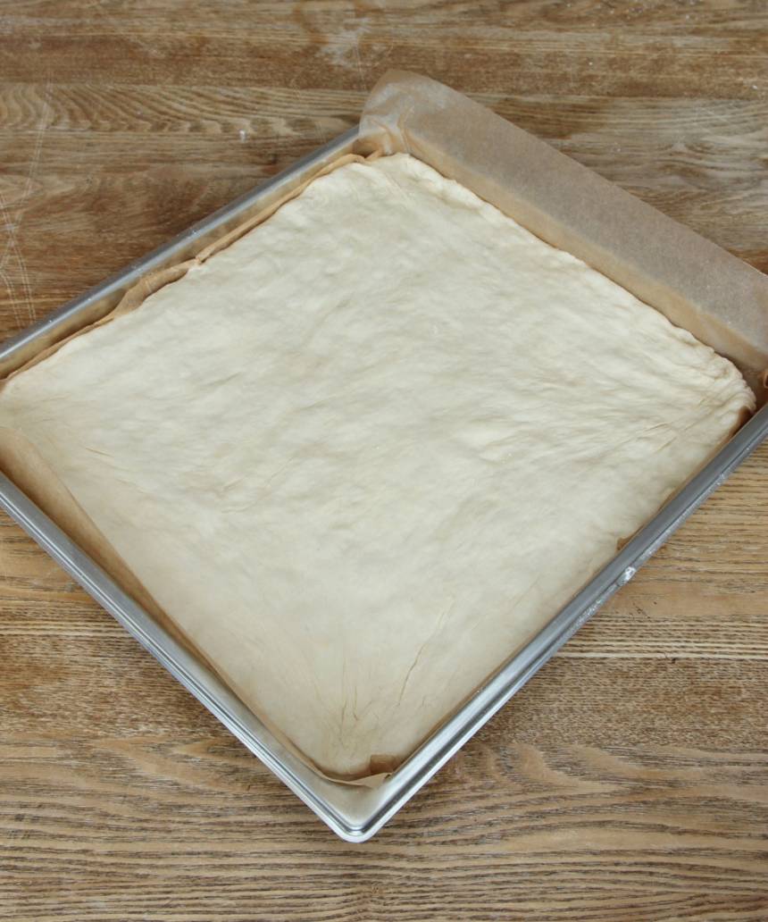 3. Tryck ut degen med mjölade händer i en långpanna, ca 29 x 32 cm, klädd med bakplåtspapper. Låt degen jäsa under bakduk i ca 30 min. Sätt ugnen på 200 grader.