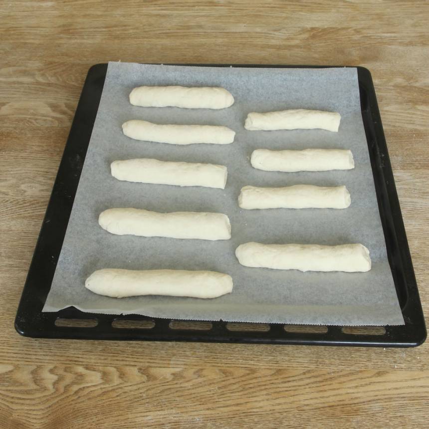 Rulla ut dem till längder, ca 12 cm. Lägg dem brett isär på en plåt med bakplåtspapper. Låt dem jäsa under bakduk i ca 30 min. Sätt ugnen på 250 grader.