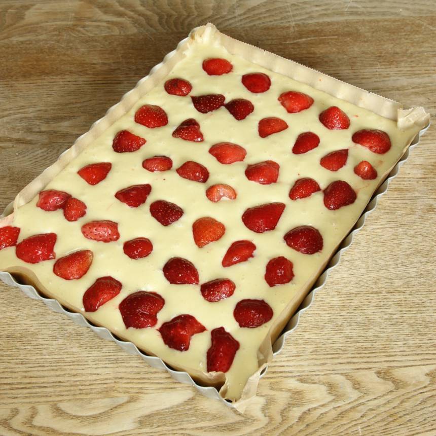 3. Häll smeten i en smord och bröad form eller klädd med bakplåtspapper, 19 x 26 cm eller en rund springform, ca 23 cm. Lägg jordgubbsbitarna ovanpå smeten.