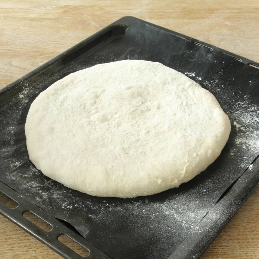 2. Knåda igenom degen och forma den till en slät boll. Lägg den på en plåt med bakplåtspapper. Platta ut degen till en rundel, ca 2 cm tjock.