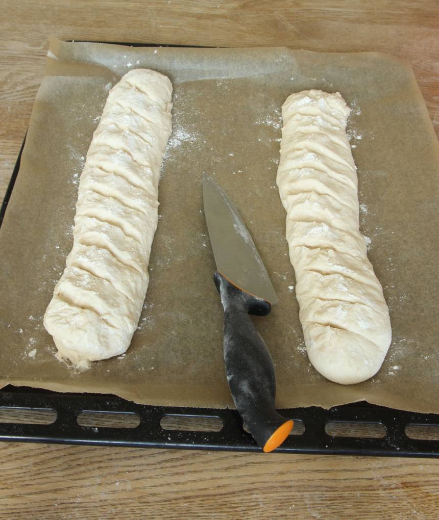 3. Lägg baguetterna på en ugnsplåt klädd med bakplåtspapper. Skär sneda snitt i baguetterna med en vass kniv. Låt dem jäsa under bakduk i ca 30 min. Sätt ugnen på 250 grader.