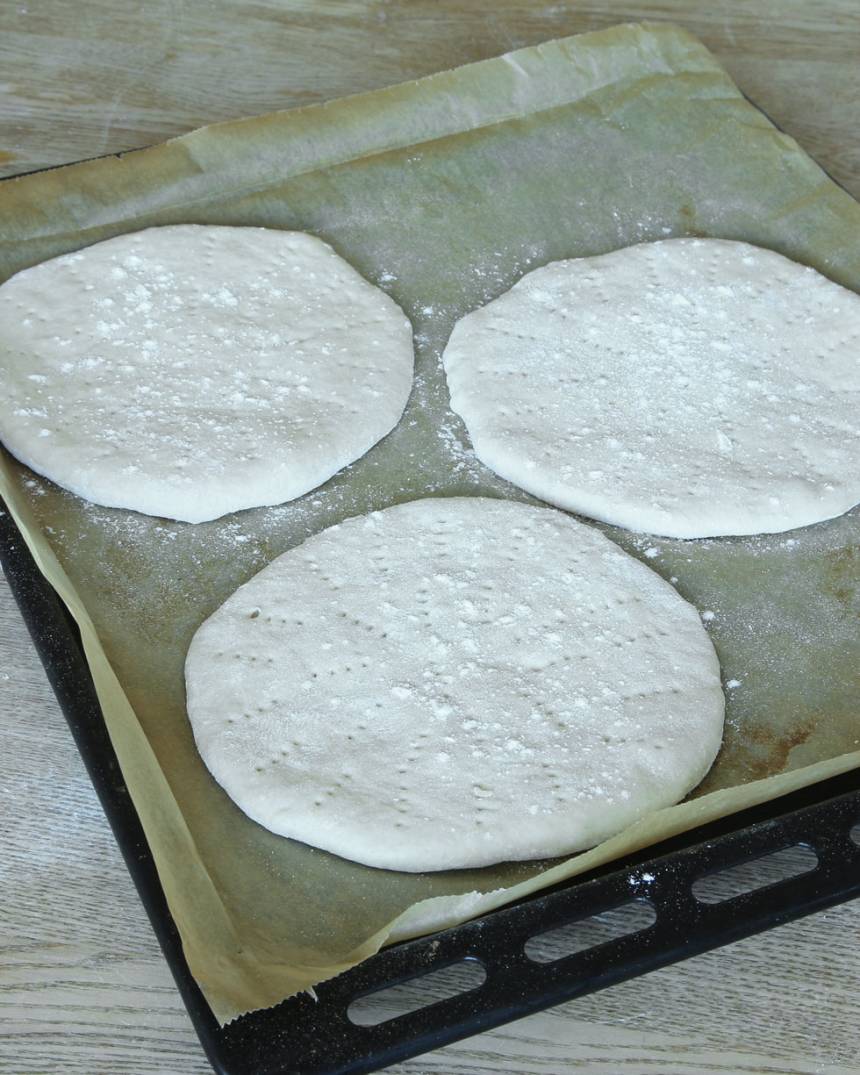 4. Strö över lite mjöl och lägg degkakorna på en plåt med bakplåtspapper. Nagga dem med en gaffel. Låt dem jäsa under bakduk i ca 30 min. Sätt ugnen på 250 grader.