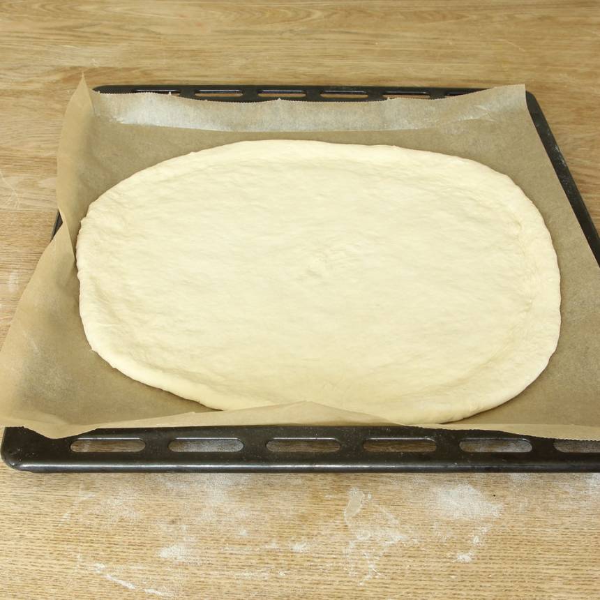 2. Knåda igenom degen på ett mjölat bakbord. Kavla ut den till en rundel, ca 1 ½ cm tjock. Lägg den på en plåt med bakplåtspapper. Låt den jäsa under bakduk i ca 30 min. Sätt ugnen på 250 grader.