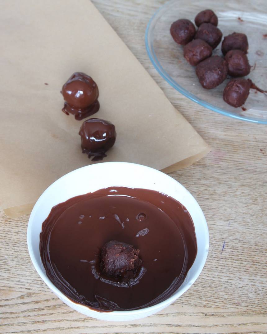 4. Forma runda bollar av chokladsmeten (ta gärna hjälp av två teskedar) och rulla dem i florsocker. Ställ dem i frysen i ca 30 min. Doppa dem i smält choklad. Lägg dem på ett bakplåtspapper och låt dem stelna i kylen.