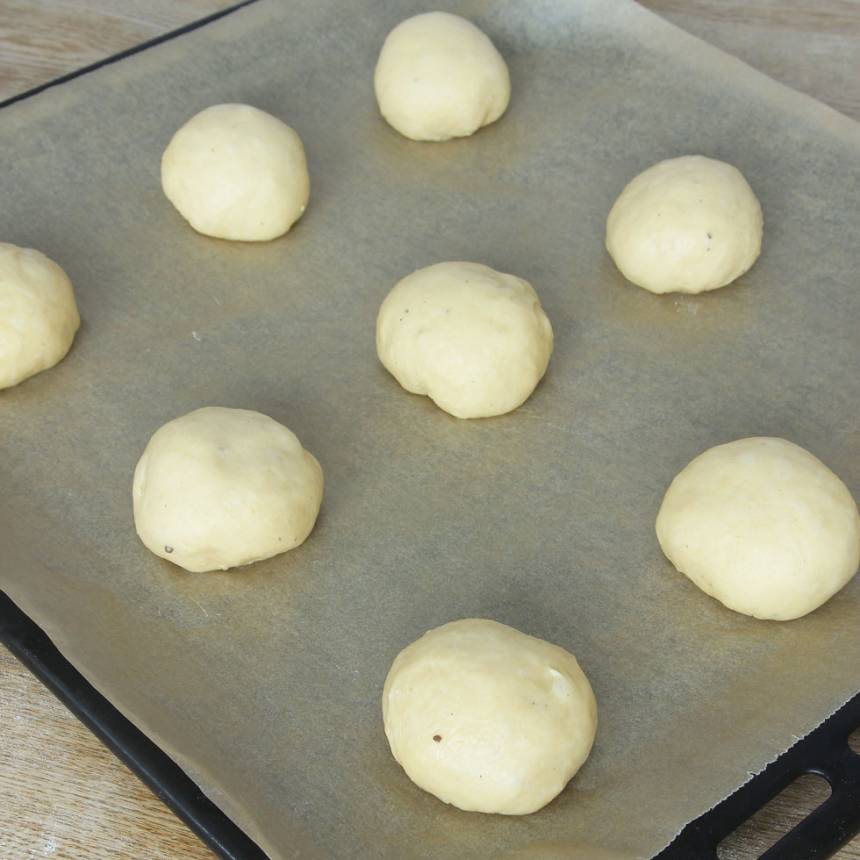 2. Knåda igenom degen på ett mjölat bakbord och dela den i ca 30 bitar. Forma släta bullar och lägg dem på en plåt med bakplåtspapper. Låt dem jäsa under bakduk i ca 45 min.