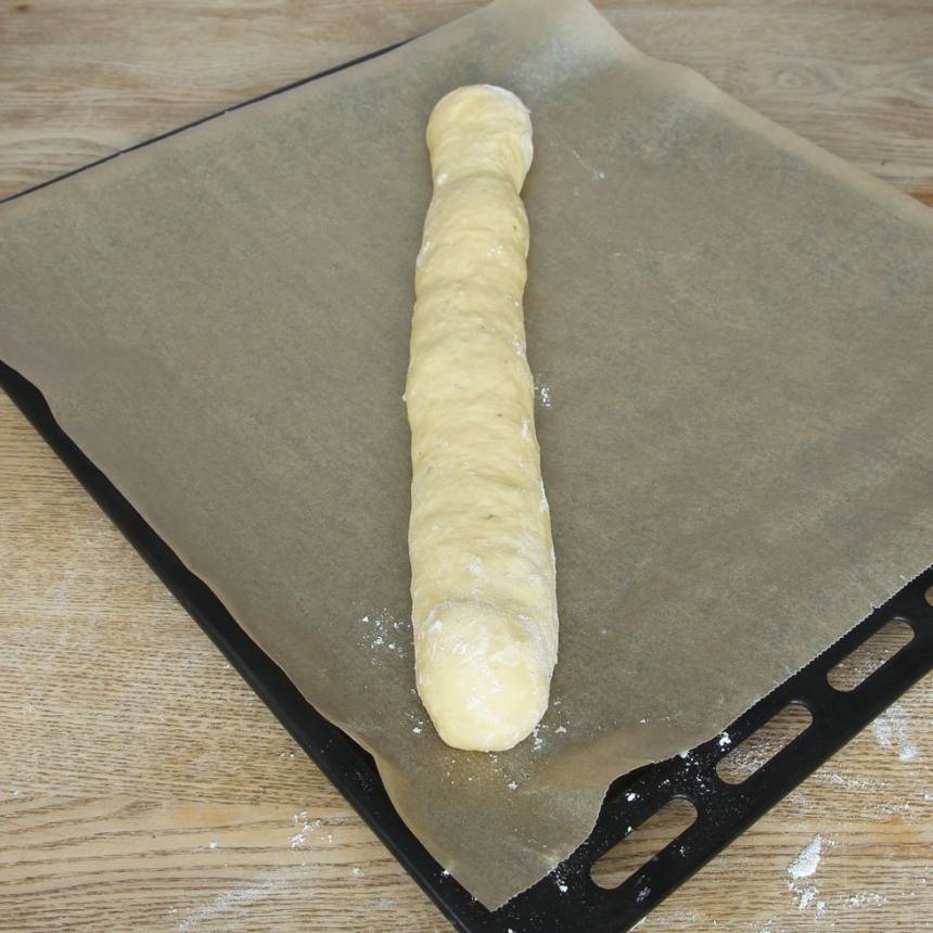 2. Knåda igenom degen på ett mjölat bakbord. Rulla ut den till en längd, lika lång som ugnsplåten. Lägg den på en plåt med bakplåtspapper.