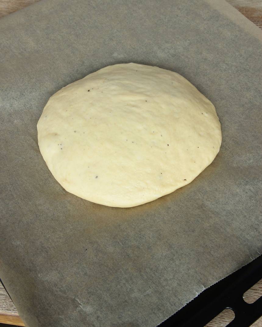 2. Knåda igenom degen på ett mjölat bakbord och forma den till en boll. Tryck ut bollen på en plåt, klädd med bakplåtspapper, ca 25 cm i diameter (degen ska vara lite rundad som en kulle). Låt degen jäsa under bakduk i ca 30 min. Sätt ugnen på 225 grader.