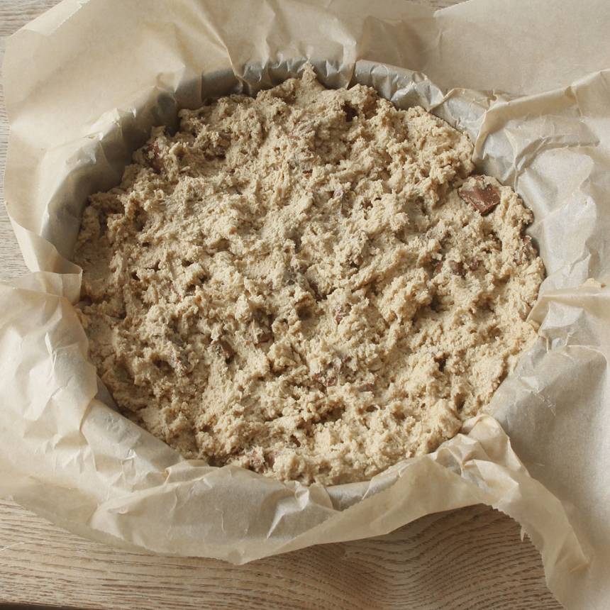 4. Smula ner degen i en smord och bröad springform, 22–23 cm i diameter. Strö över resten av den grovhackade chokladen.