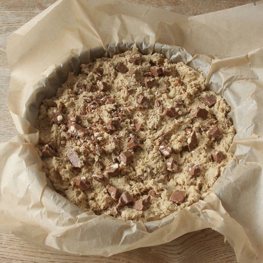 4. Smula ner degen i en smord och bröad springform, 22–23 cm i diameter. Strö över resten av den grovhackade chokladen.