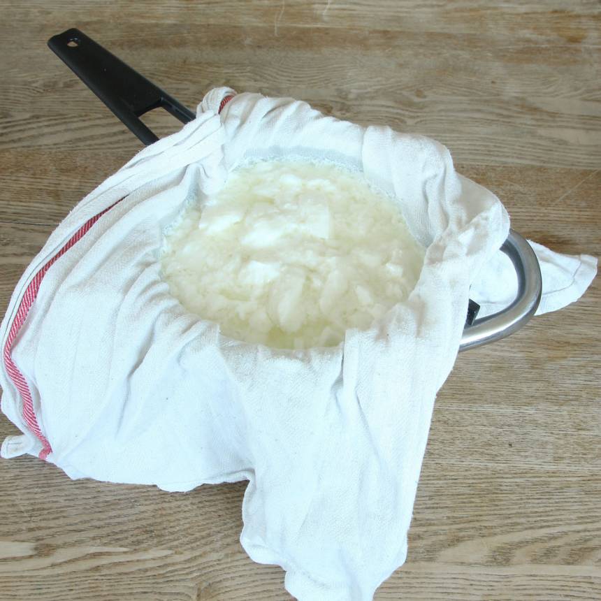 4. Sila bort vätskan från yoghurten. Lägg en ren kökshandduk i ett durkslag. Häll i yoghurten och låt vätskan rinna av.