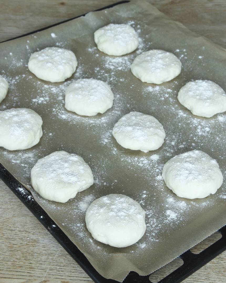 3. Forma runda bullar av degbitarna med mjölade händer. Lägg dem på en plåt med bakplåtspapper och platta till dem något. Strö över lite vetemjöl.