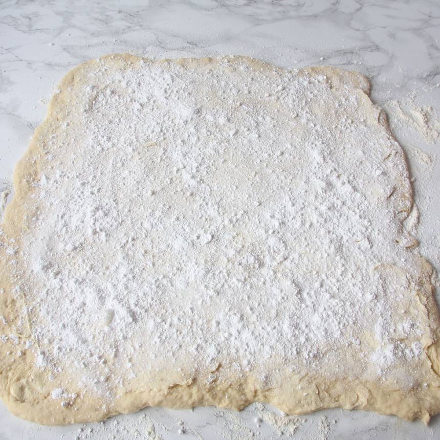 3. Bred ut hälften av smöret på degplattan och strö över hälften av vaniljsockret och florsockret.