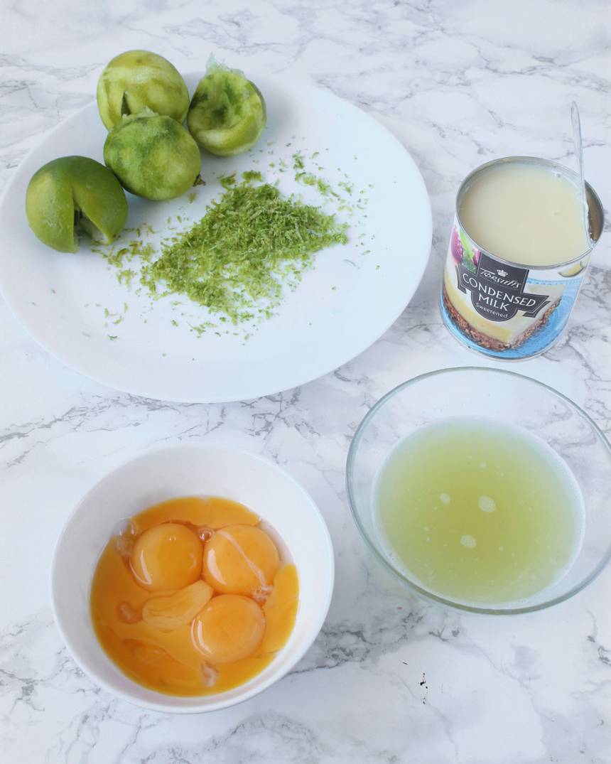 4. Fyllning: Sätt ugnen på 150 grader. Vispa ihop äggulorna lätt i en skål med en vanlig handvisp. Finriv ca 1 msk limeskal. Pressa ur 1 dl limejuice från limefrukterna. Öppna burken med kondenserad mjölk.