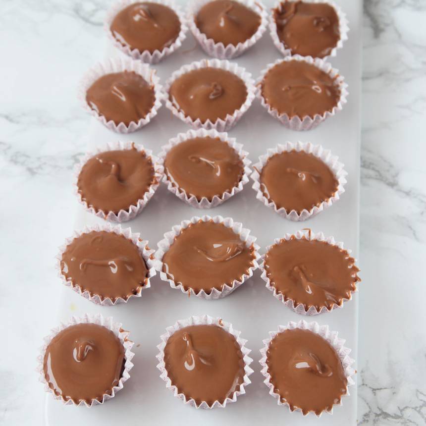 5. Smält mjölkchokladen (eller nougat) över vattenbad och lägg en klick som smälter ut ovanpå kolasmeten. Låt det stelna i frysen i några minuter.