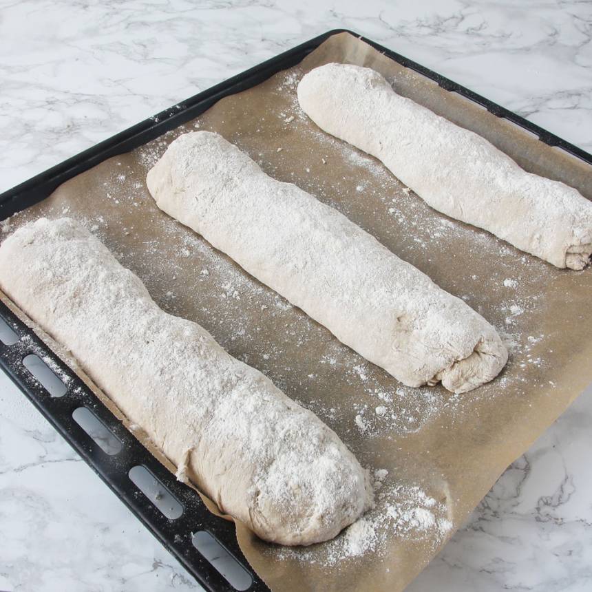 3. Forma degbitarna till längder (lika långa som kortsidan på din ugnsplåt). Rulla dem i lite vetemjöl och lägg dem på en plåt med bakplåtspapper. Låt limporna jäsa under bakduk i ca 30 min. Sätt ugnen på 250 grader.