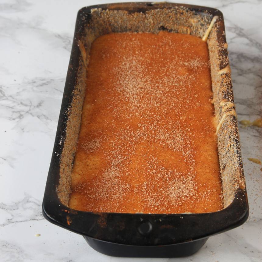4. Häll över hälften av smeten som är kvar i bunken. Pudra på hälften av kanel- och sockerblandningen. Häll över den sista smeten och pudra över den sista kanel- och sockerblandningen.