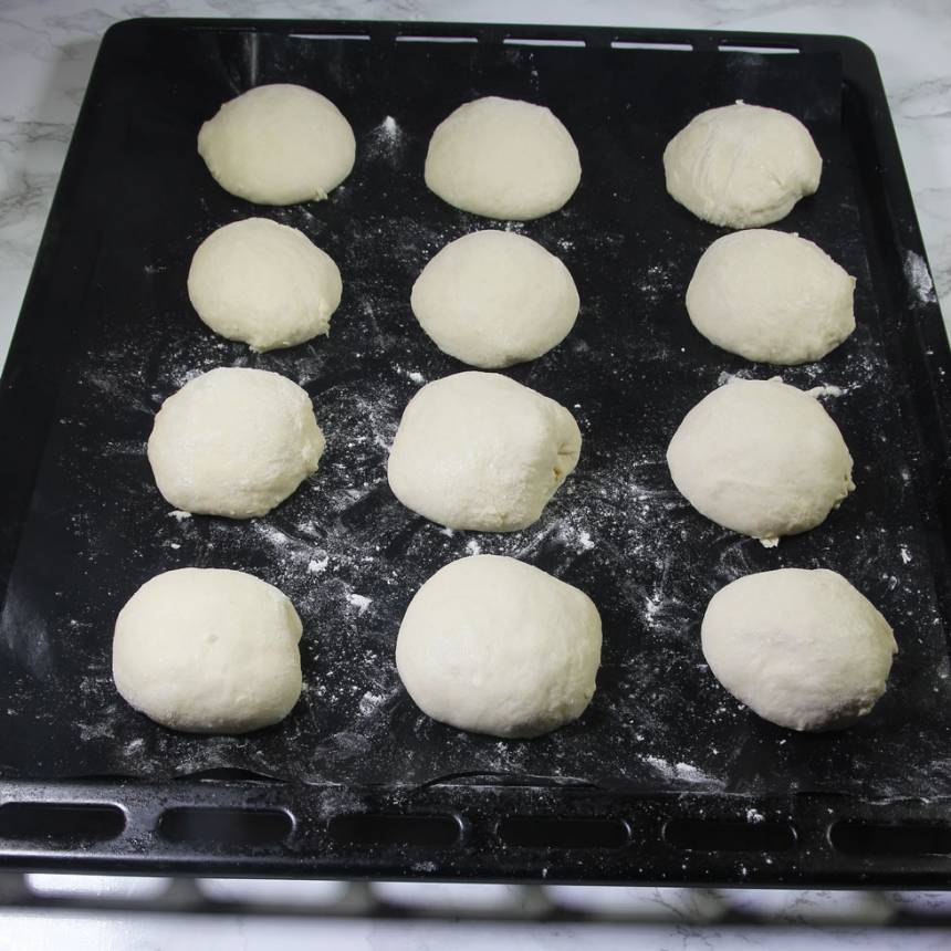 2. Dela degen i ca 20 bitar. Forma dem till runda bullar med mjölade händer. Lägg dem på en plåt med bakplåtspapper. Låt dem jäsa under bakduk i ca 30 min. Sätt ugnen på 250 grader.